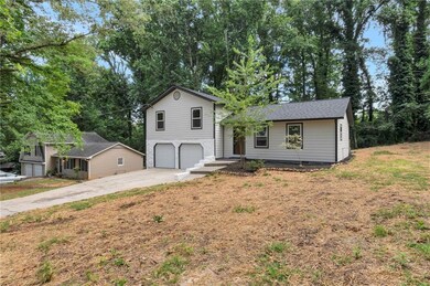 Split level home featuring a garage, driveway, and view of wooded area
