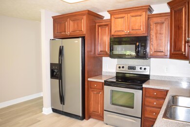 Kitchen with light wood-style flooring, light countertops, brown cabinetry, appliances with stainless steel finishes, and a sink