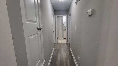 Hall with baseboards and dark wood-type flooring