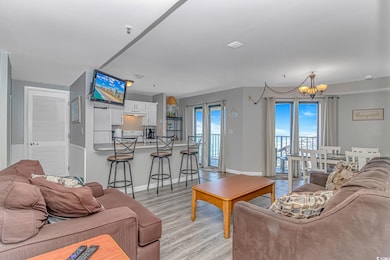 Living room featuring a chandelier, light wood finished floors, and baseboards