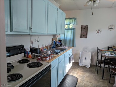 Kitchen featuring tile floors, sink, ceiling fan, and range