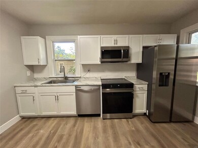 Kitchen with white cabinetry, light hardwood / wood-style floors, appliances with stainless steel finishes, and sink