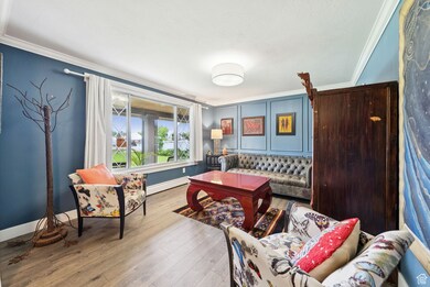 Living area featuring ornamental molding, wood finished floors, and baseboard heating