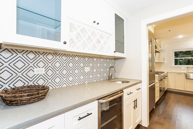 Custom glass front cabinetry, tile backsplash and 