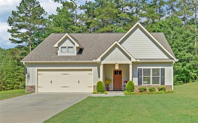 Craftsman house with board and batten siding, a garage, a front lawn, roof with shingles, and stone siding