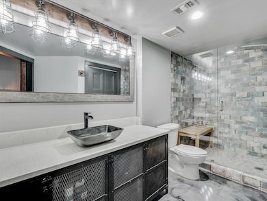 Bathroom with a shower with door, vanity, and toil