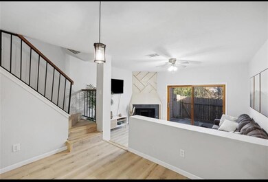 Cozy living space with wood-burning fireplace, sliding glass doors to private fenced patio, and natural light throughout.