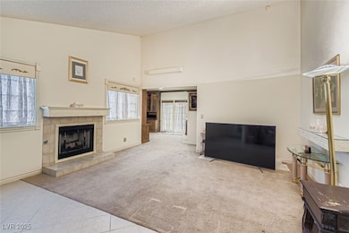 Living room featuring light carpet, light tile patterned flooring, high vaulted ceiling, a textured ceiling, and a fireplace
