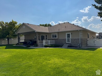 Rear view of property featuring a gate, a patio, stucco siding, and stone siding
