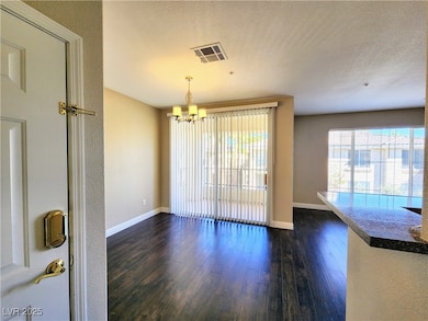 Unfurnished dining area with a chandelier, dark wood-style flooring, baseboards, and a textured ceiling