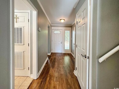 Entryway with wood-type flooring and crown molding