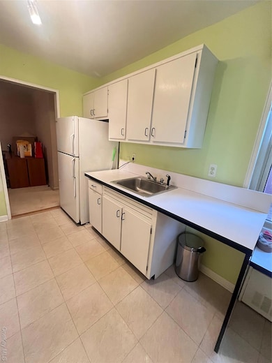 Kitchen with white cabinets, refrigerator, and light tile patterned floors
