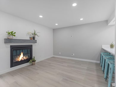 Unfurnished living room featuring recessed lighting, light wood-type flooring, and a glass covered fireplace