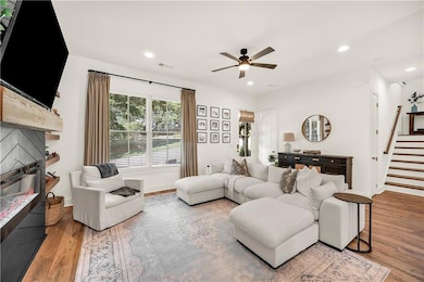 Living room with a ceiling fan, wood finished floors, stairs, and recessed lighting