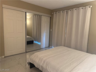 Bedroom with a textured ceiling, marble finish flo