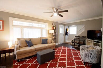 Spacious living room features hardwood flooring, ceiling fan, and decorative fireplace.