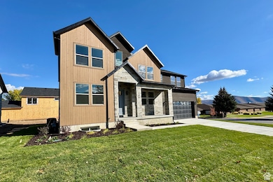 View of front of property with concrete driveway, a front yard, stone siding, a porch, and an attached garage