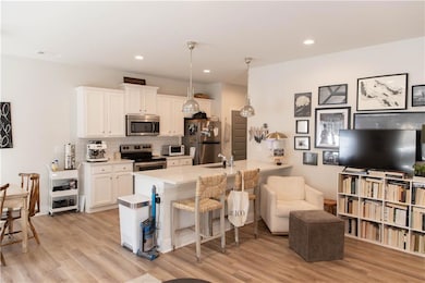 Kitchen featuring appliances with stainless steel finishes, a sink, backsplash, white cabinetry, and light wood finished floors