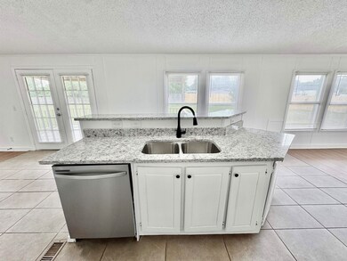 Kitchen with dishwasher, a sink, light tile patterned flooring, plenty of natural light, and a textured ceiling