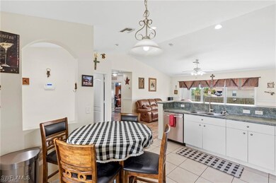 Kitchen with light tile patterned flooring, white cabinetry, vaulted ceiling, open floor plan, and dark countertops