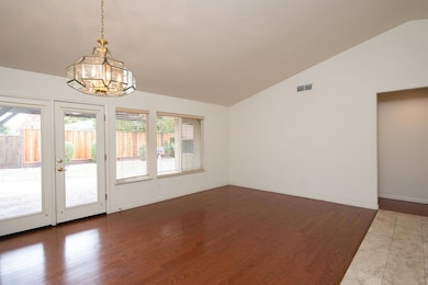 Dining / Living combo area featuring wood finished floors, vaulted ceiling, and French doors leading to the backyard.
