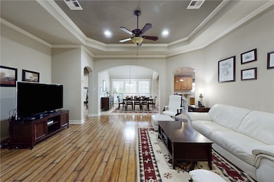 Living room with arched walkways, a raised ceiling