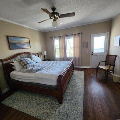 Bedroom with ceiling fan, a textured ceiling, orna