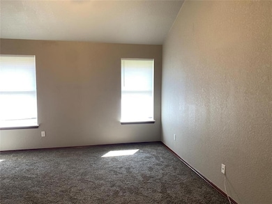 Carpeted spare room featuring a textured wall and baseboards