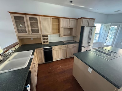 Kitchen with a sink, freestanding refrigerator, tasteful backsplash, dark countertops, and dark wood-type flooring