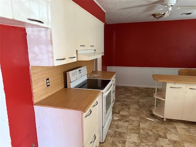 Kitchen featuring white range with electric stovetop, light countertops, a textured ceiling, extractor fan, and decorative backsplash