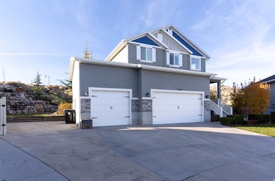 View of front facade with driveway, an attached garage, stone siding, and stucco siding