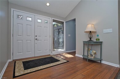 Foyer with hardwood floors and vaulted ceiling.