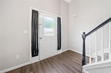 Foyer featuring baseboards, stairs, and wood finis