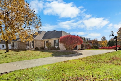 View of front of house featuring a front lawn, driveway, brick siding, and a garage