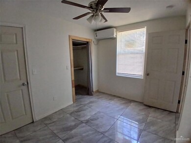 Unfurnished bedroom featuring a wall mounted air conditioner, ceiling fan, a closet, and baseboards