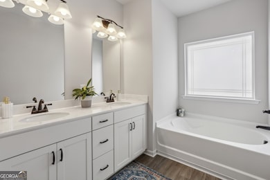 Primary Ensuite Bathroom With A Soaking Tub, Separate Walk-In Shower, & Dual Vanities