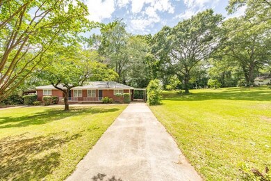 View of front of house featuring driveway, a porch, a front lawn, and brick siding