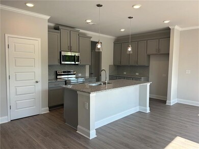 Kitchen featuring stainless steel appliances, gray cabinets, a kitchen island with sink, stone counters, and decorative backsplash