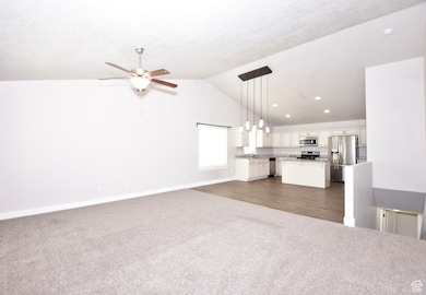 Unfurnished living room featuring dark carpet, vaulted ceiling, ceiling fan, and recessed lighting
