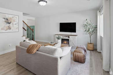 Living area with a glass covered fireplace, light wood-type flooring, and stairway