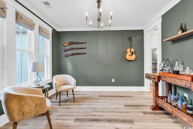 Living area featuring ornamental molding, light wood-style floors, a chandelier, and baseboards