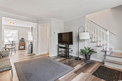 Living room featuring light wood-style floors, stairway, a textured ceiling, and ornamental molding