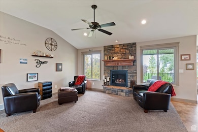 Living area featuring lofted ceiling, a fireplace, ceiling fan, light colored carpet, and recessed lighting