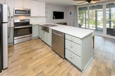 Kitchen featuring appliances with stainless steel finishes, a sink, a peninsula, open shelves, and backsplash