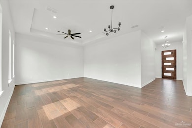 Empty room featuring a raised ceiling, wood finished floors, and visible vents