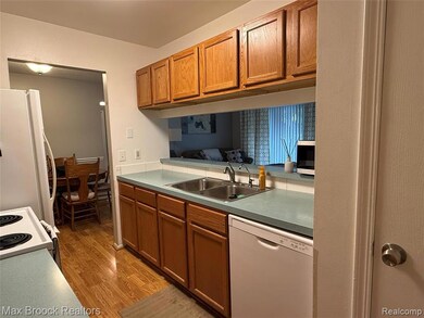 Kitchen featuring white appliances, brown cabinets, light wood-style floors, and light countertops