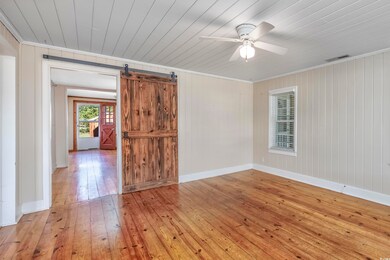 Spare room featuring a barn door, wooden walls, li