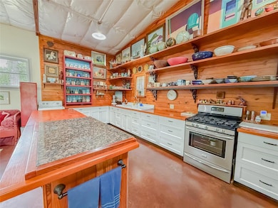 Kitchen featuring gas range, open shelves, white 