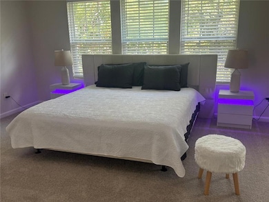 Carpeted bedroom featuring multiple windows