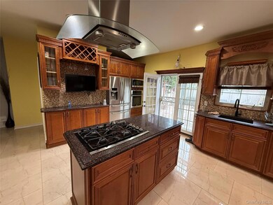 Kitchen with glass insert cabinets, backsplash, light marble finish floors, dark stone countertops, and recessed lighting